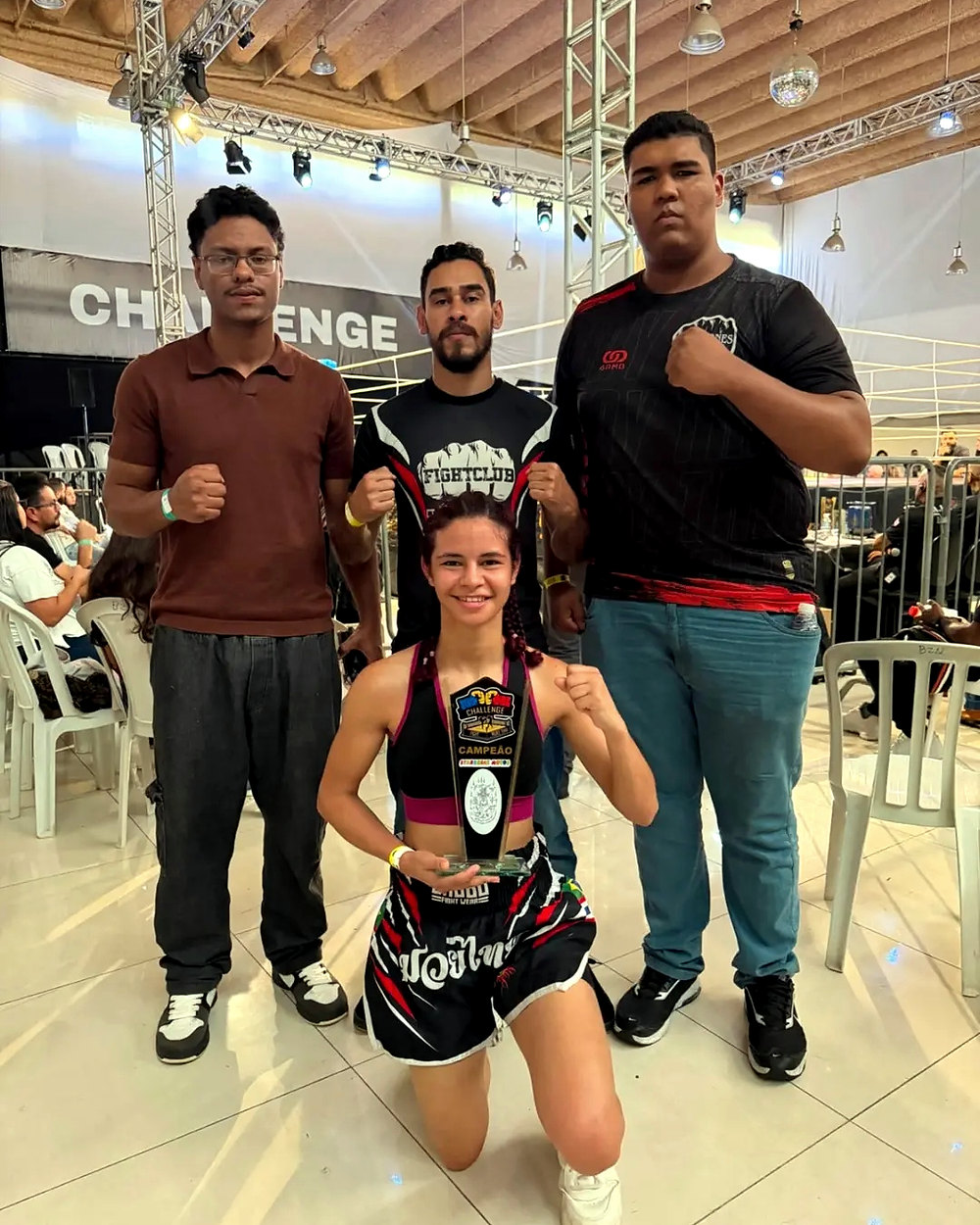Atleta Mariana com o cinturão ao lado da equipe no Challenge